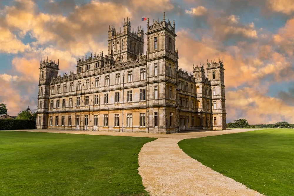 Majestic Highclere Castle in England with a beautiful sunset sky and light rays.