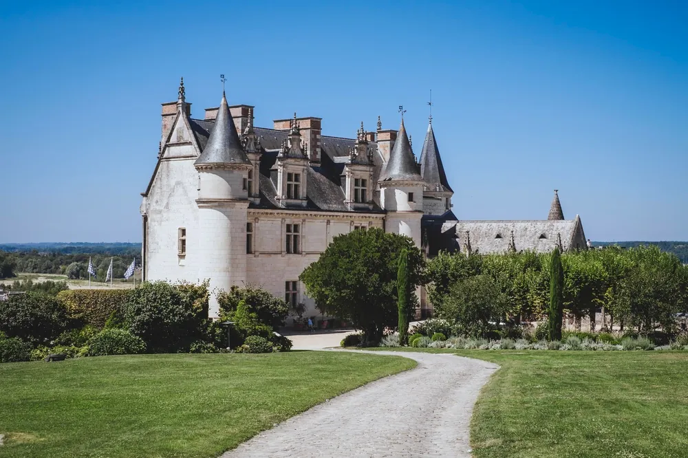 A view of the historic town of Amboise at the side of the River Loire, with the illuminated royal castle Chateau d'Amboise towering at the hilltop. Amboise, Loire Valley, France. 12 August 2025