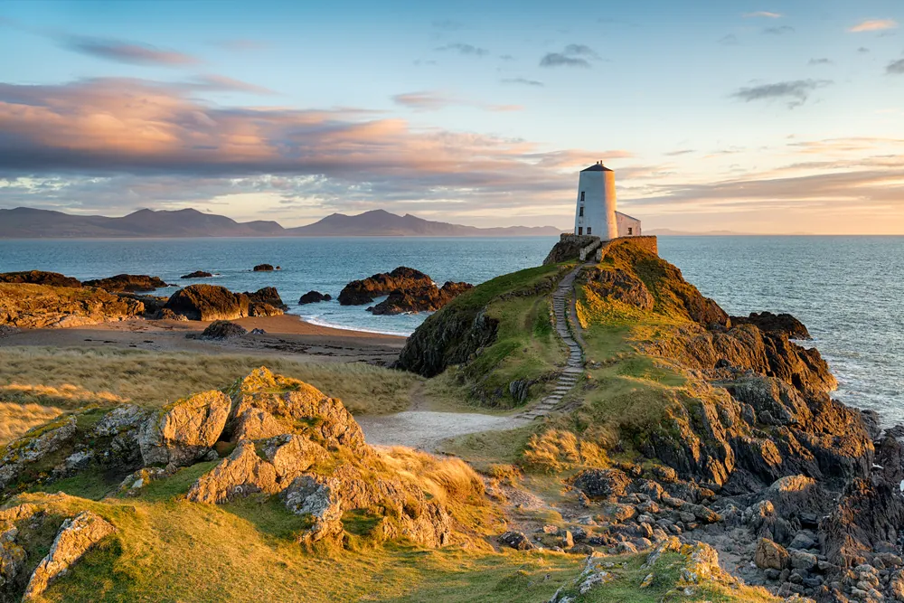 Sunset at Ynys Llanddwyn island on the coast of Anglesey in North Wales with the mountains of Snowdonia in the distance.
