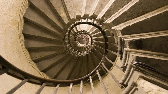 A spiral staircase winding up a castle tower